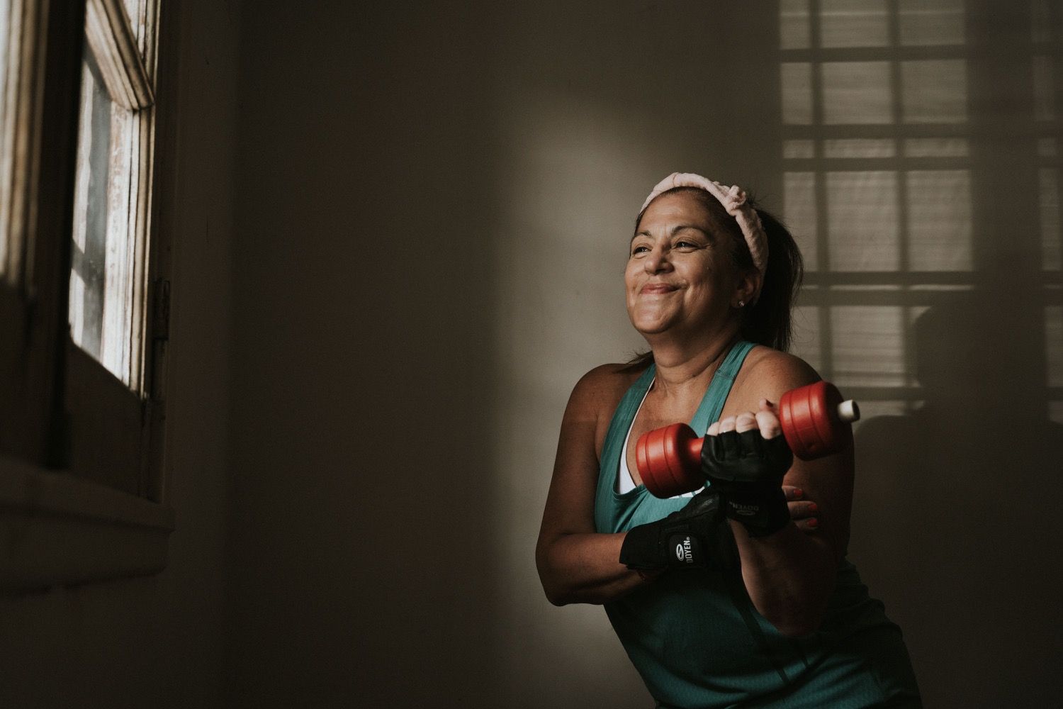A woman doing a dumbbell curl during a strength workout in natural window light